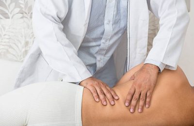 Osteopath or Physiotherapist messaging his patient's back and waist.