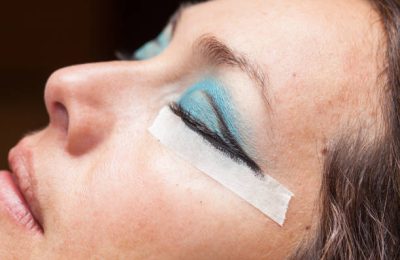 Close up of a woman while make up artist creates cat eyes